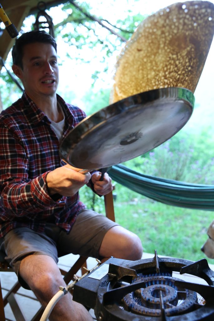crêpière en inox avec une crêpe dorée en train de cuire, elle saute pour la retourner.