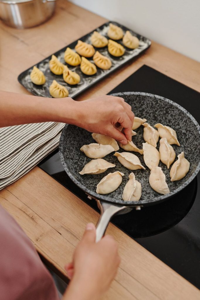 person cooking dumplings in the pan
